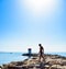 Silhouette of a young guy on the stones of the breakwater,  by the end of which stands a lighthouse