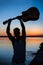 Silhouette of young handsome man holding guitar at seaside during sunrise.