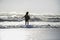 Silhouette of young happy Asian woman relaxed looking at wild sea waves on sunset tropical beach