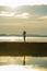 Silhouette of young happy man with his little son or daughter in his arms , the father raising up the baby in front of the sea at