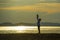 Silhouette of young happy man with his little son or daughter in his arms , the father raising up the baby in front of the sea at