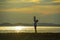 Silhouette of young happy man with his little son or daughter in his arms , the father raising up the baby in front of the sea at