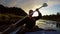 Silhouette of young happy man paddling kayak at sunset, slow-mo