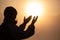 Silhouette of young human hands open palm up worship and praying to god at sunrise, Christian Religion concept background