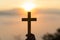 Silhouette of young human hands praying with a cross at sunrise, Christian Religion concept background