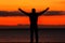 Silhouette of a young man against the background of the crimson sunset