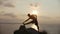 Silhouette of young man doing morning gymnastics on rocky cliff by the river at sunrise