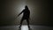 Silhouette of a young man in hood performing hip hop moves on a stage with spotlight in the background -