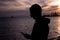 Silhouette of a young man with a phone in hands on the background of a beautiful sunset sky by the sea