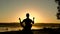 Silhouette of young man practicing meditation on the beach at sunset. 4K