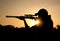 Silhouette of a young man shooting with a rifle