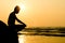 Silhouette of young man sitting on the edge of rock