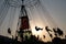 Silhouette of young people on Ferris wheel and swinging carousel in stop motion on sunset background