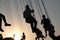 Silhouette of young people on Ferris wheel and swinging carousel in stop motion on sunset background