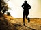 Silhouette of young sport man running on countryside in cross country workout at summer sunset