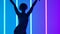 Silhouette of a young stylish girl dancing against the background of multicolored neon tubes. The girl gracefully moves