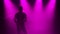 Silhouette a young stylish guy plays the golden shiny saxophone in the multicolored spotlights on stage. Dark studio