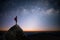 Silhouette of young traveler and backpacker standing on the rock watched the star and milky way. He enjoyed traveling and was