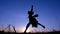 Silhouette of young witch jumping on the broomstick at sunset
