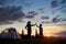 Silhouette of young woman and child giving each other high five near camping at dawn on top of mountain