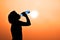 Silhouette of young woman drinking water ( thirsty, hot feeling a need to drink water)