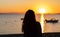 Silhouette of a young woman in front of a sunset on the beach, with boats and mountains. Vacation relax scene in Mar Menor, Murcia