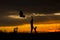 Silhouette of a young woman and her dog at sunset. Outdoors. She is holdings balloons. Love for animals concept