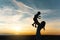 Silhouette of young woman high toss up little cute child baby boy on nature, sunset horizon background. Mother throw up