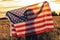 Silhouette of Young Woman Holding USA Flag in Field at Sunset