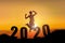 Silhouette of young woman jumping on the hill with 2020 happy new years