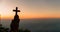 Silhouette of young woman kneeling down praying and holding christian cross for worshipping God at sunset background. concept of