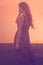 Silhouette of a young woman with long hair enjoying beautiful sunset in the lavender field. Back view of a romantic girl holding