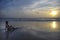 Silhouette of young woman lying on sand looking to sea sunset horizon with beautiful sun