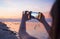 Silhouette of young woman with mobile phone camera taking picture of beautiful beach sunset landscape and mount Agung volcano of B