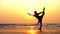 Silhouette of young woman performing rhythmic gymnastics element on the beach