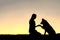 Silhouette of Young Woman and Pet Dog Shaking Hands at Sunset