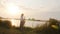 Silhouette of a young woman playing on the saxophone near the riverbank at dawn, a beautiful girl in a long dress with a wind musi