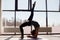 Silhouette of a young woman practicing the concept of yoga, performing a handstand, against the background of panoramic Windows