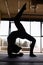 Silhouette of a young woman practicing the concept of yoga, performing a handstand, against the background of panoramic Windows