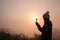 Silhouette of young woman praying with a cross at sunrise, Christian Religion concept background