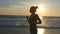 Silhouette of young woman running on sea beach at sunset. Girl jogging along ocean shore during sunrise. Female