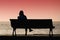 Silhouette of young woman sitting alone on the bench