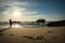 Silhouette of young woman standing on scenic sandy beach taking photos of beautiful seascape of atlantic ocean with waves in sunny