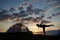 Silhouette of young woman stretching on top of mountains at sunset near camping against beautiful sky