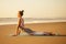 Silhouette of young woman in a stylish suit for yogi jumpsuit doing yoga on the beach in pose copy space