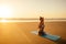 Silhouette of young woman in a stylish suit for yogi jumpsuit doing yoga on the beach in pose copy space
