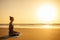 Silhouette of young woman in a stylish suit for yogi jumpsuit doing yoga on the beach in pose copy space