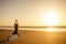 Silhouette of young woman in a stylish suit for yogi jumpsuit doing yoga on the beach in pose copy space