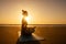 Silhouette of young woman in a stylish suit for yogi jumpsuit doing yoga on the beach in pose copy space