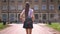 Silhouette of young woman walks along to university in park in daytime in summer